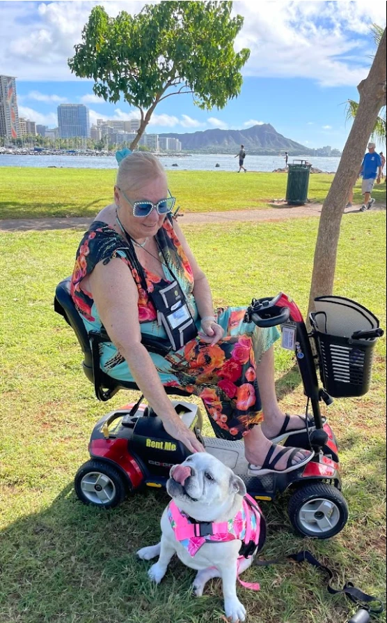 Traveler on a mobility scooter with a dog at a park overlooking Waikiki